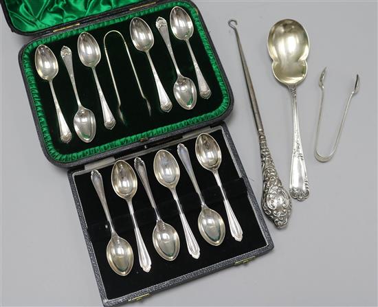 Two cased sets of six silver teaspoons, one with tongs, a silver serving spoon, silver handles button hook and a pair of tongs.